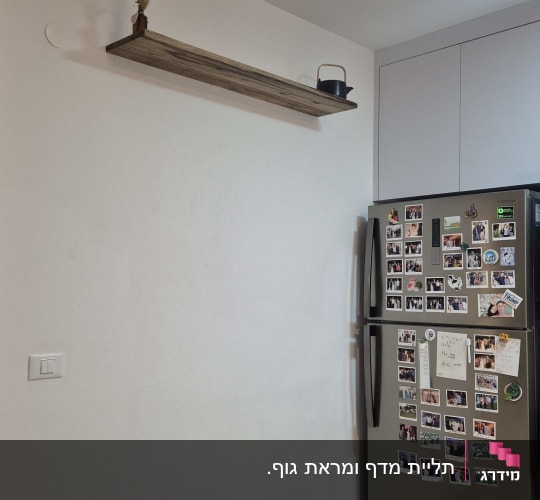 מדף עץ מותקן על קיר ליד מקרר עם מגנטים